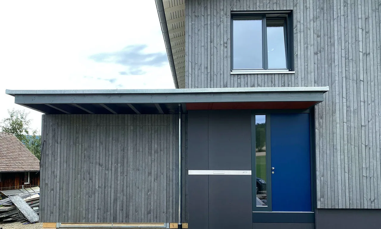 Hauseingang mit blauer Tür unter Vordach, Aussenansicht